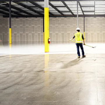 Two workers sweeping a warehouse floor