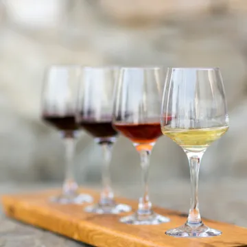 Four glasses of wine on a wooden platter