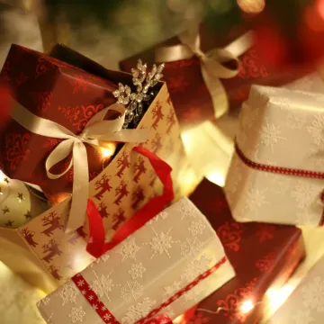 Beautifully wrapped Christmas presents under the tree with festive decorations and ribbons.