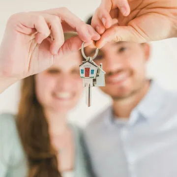 Young couple holding keys to their new home, symbolizing a fresh start and investment in real estate.