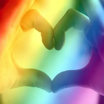 Hands forming a rainbow heart shape, symbolizing
