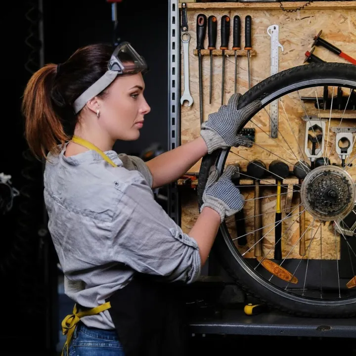 Beautiful female in working clothes, apron and goggles, repa
