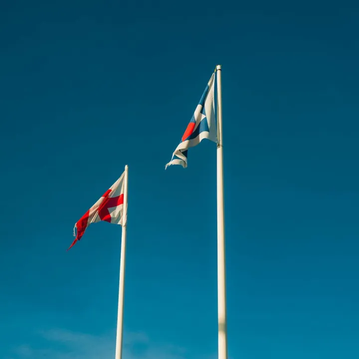 Two flags on poles against a clear blue sky