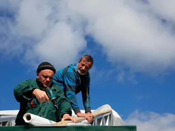 People working on rooftop against sky