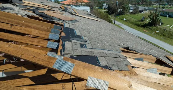 Damaged house roof with missing shingles after hurricane Ian