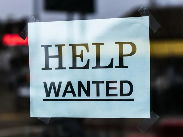 Close-up of a Help Wanted sign taped to a glass