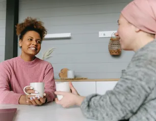 Two women share a joyful coffee moment at home