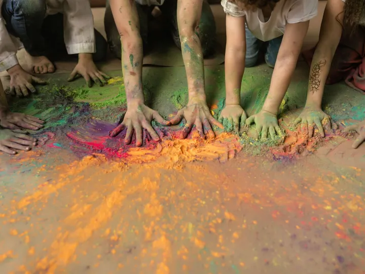 Children's hands mixing brightly coloured craft powder at Messy Church