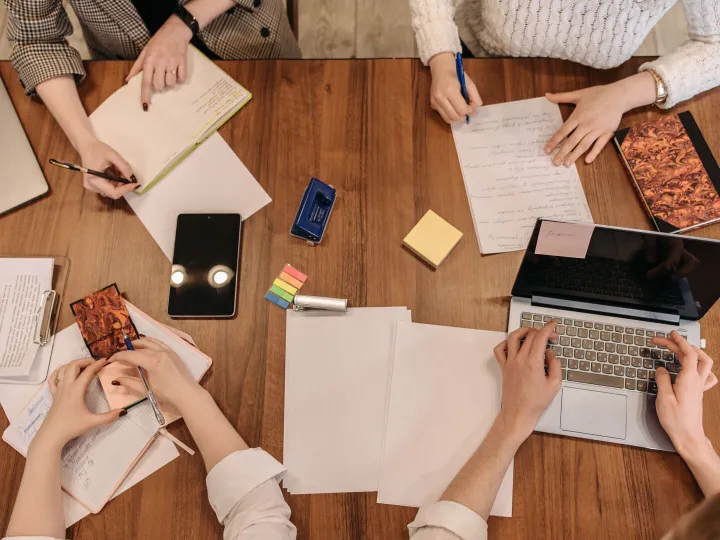 A team planning together around a wooden table with notes and a laptop