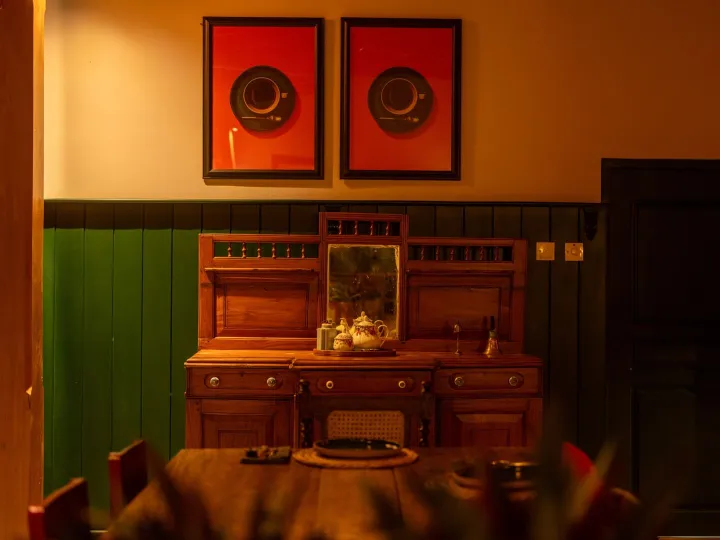 Antique teak furniture beside the main dining table at night at Peacock Hill Sigiriya