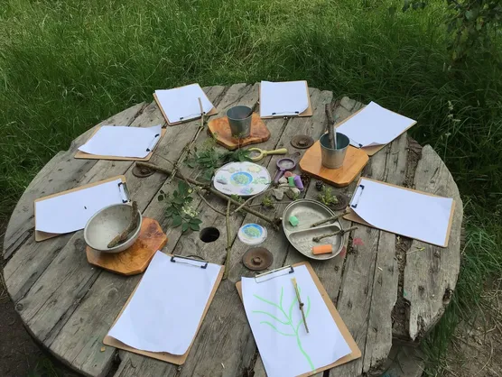 Clipboards and paper arranged in a circle on the cable drum table for drawing