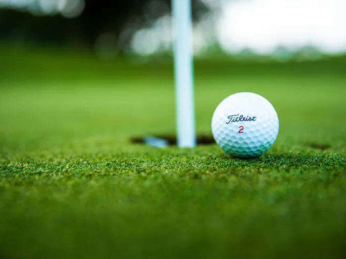 Close-up photo of a golf ball near the hole.