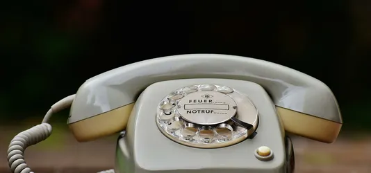 Close-up of a vintage rotary dial telephone with a nostalgic design on a wooden surface.
