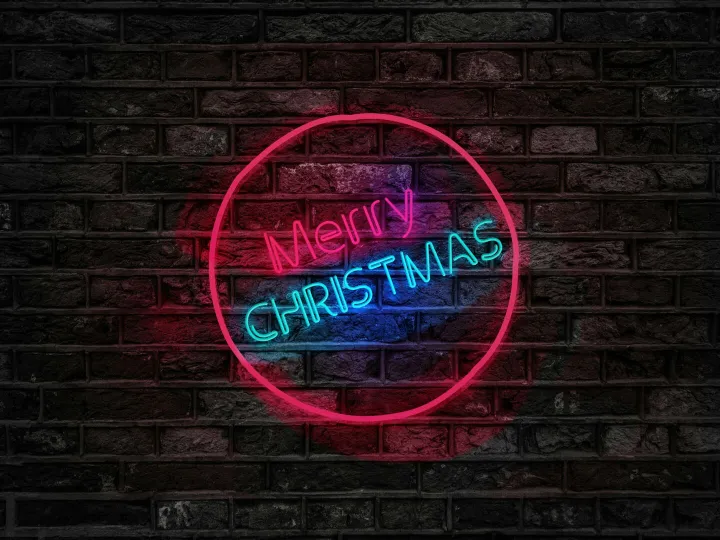 Vibrant neon Merry Christmas sign glowing on a dark brick wall, perfect for holiday themes.