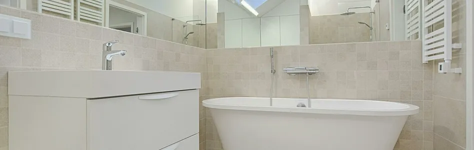 Elegant minimalist bathroom featuring a white bathtub and sleek fixtures.