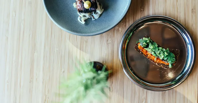 Elegant plating of gourmet dishes on wooden table, showcasing fine dining artistry.