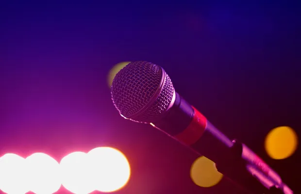 Colorful stage lighting highlights a microphone in a close-up view, perfect for music and performance themes.