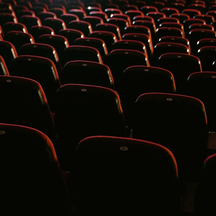 Rows of empty red seats in a dimly lit movie theater, showcasing a cinema environment.