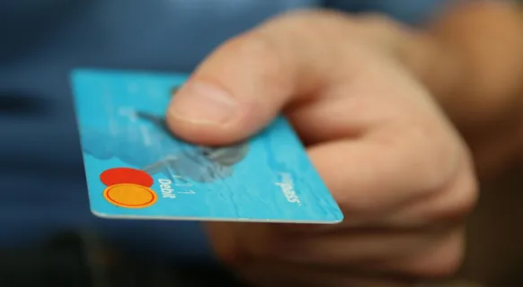 A close-up shot of a hand offering a blue debit