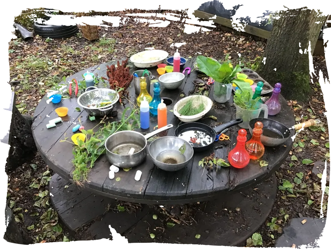 Pans, bowls and potion bottles set out on the mud kitchen table