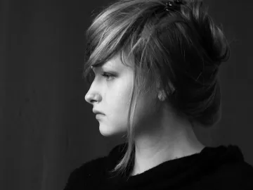 Profile black and white portrait of a young woman with styled hair, looking thoughtful.