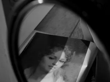 A grayscale photograph showcasing a vintage portrait reflected in a mirror, evoking a classic and artistic feel.