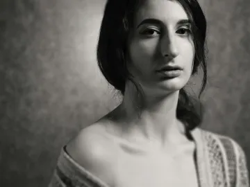 A striking black and white portrait capturing the elegance and introspection of a young woman in a studio setting.