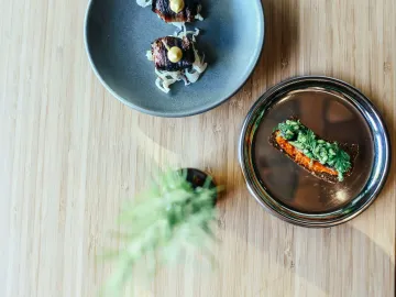 Elegant plating of gourmet dishes on wooden table, showcasing fine dining artistry.