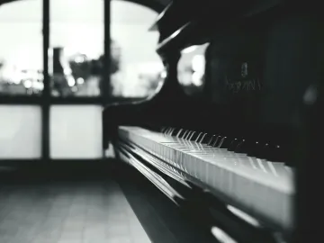Stylish black and white close-up of a piano inside a room with soft lighting.