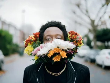 Creative portrait of a man with floral arrangement outdoors, blending art and nature.