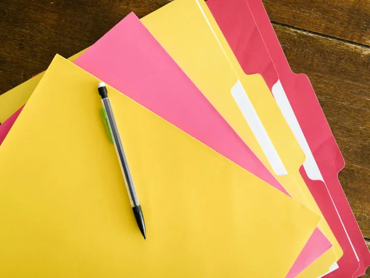 Colorful folders and pen arranged on a wooden