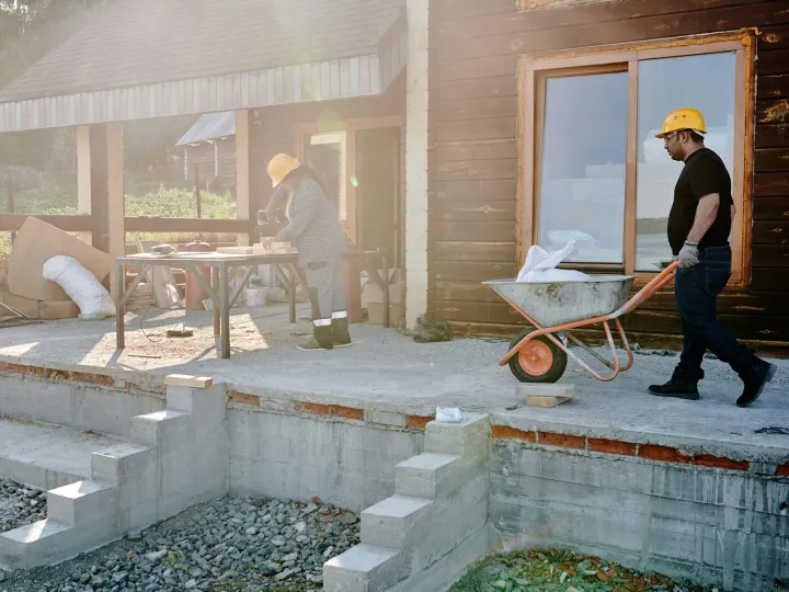 Two construction workers renovating a house exteri