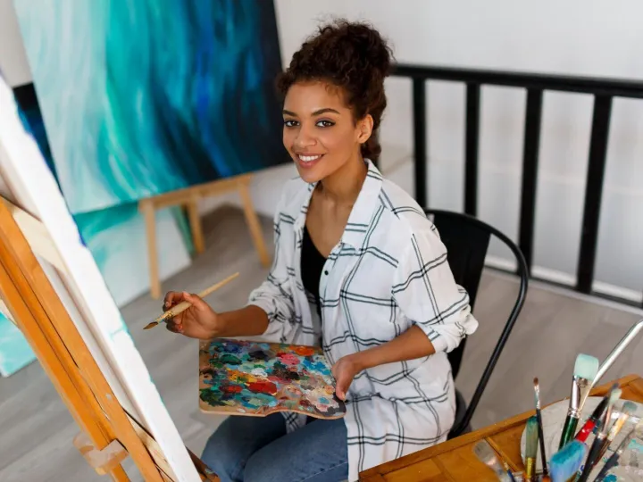 Portrait of professional female artist painting on canvas in