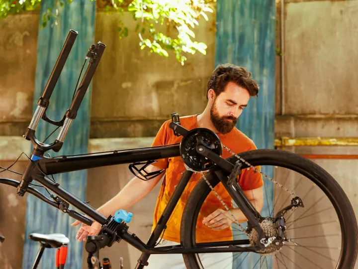 Athletic male repairs modern bicycle