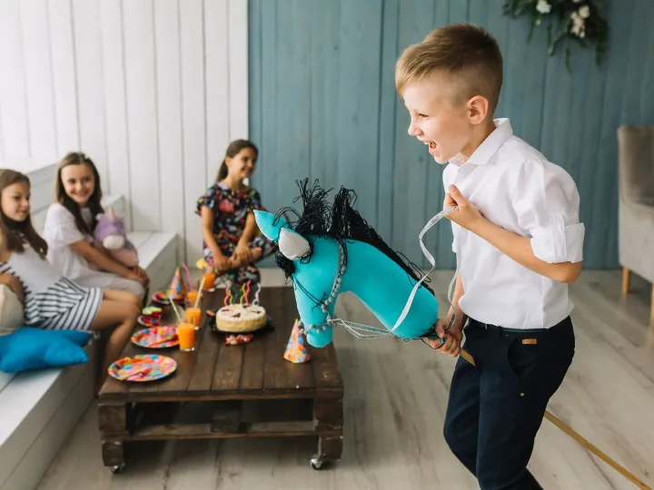 Boy riding hobby horse on birthday party