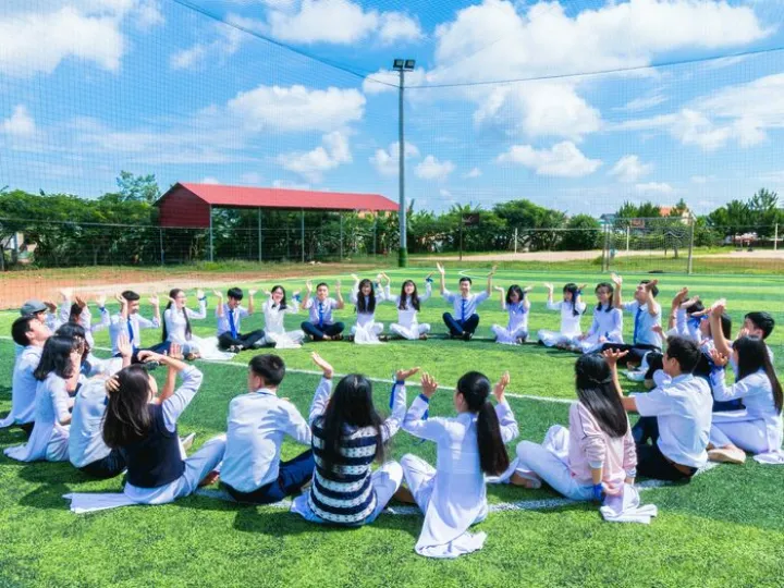 People Sitting on Green Lawn Grass While Doing Hands Up at Daytime
