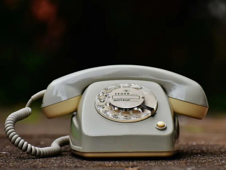 Close-up of a vintage rotary dial telephone with a nostalgic design on a wooden surface.
