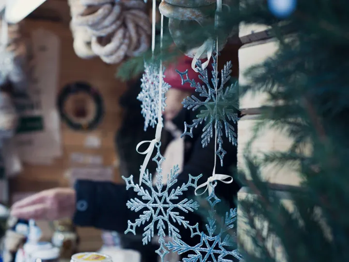 Beautiful snowflake ornaments hanging at a bustling outdoor Christmas market.