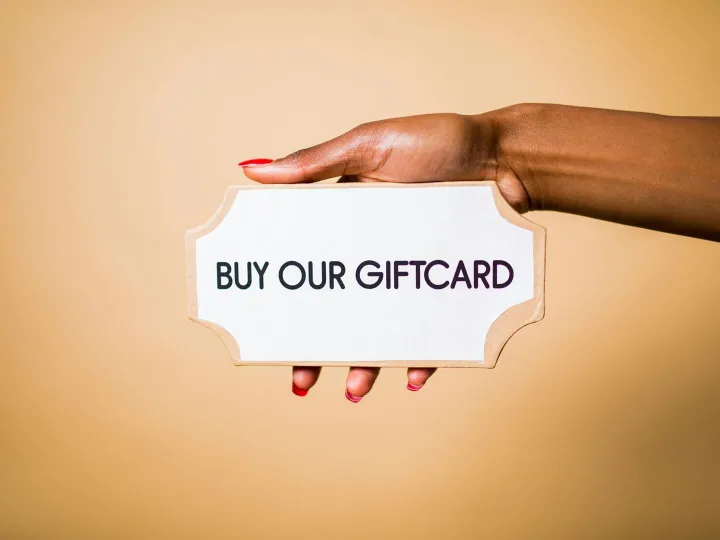 Close-up of a hand holding a 'Buy Our Giftcard
