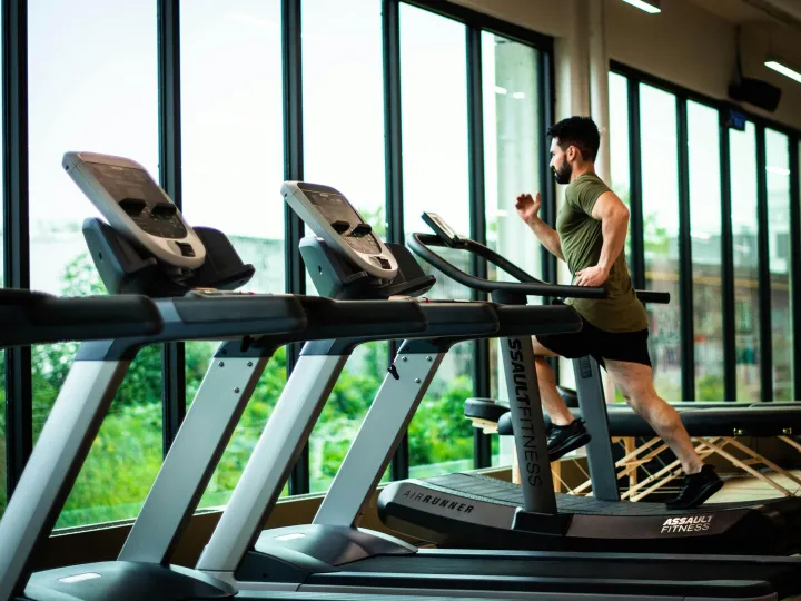 Young man workouts on treadmill in modern gym with